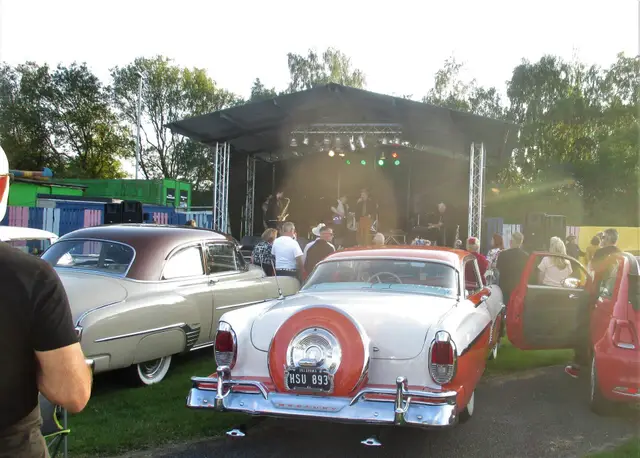 A white and red 1950s car in front of the rally stage