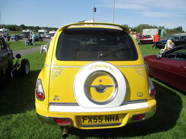 A yellow car with a chrome spare wheel on the back