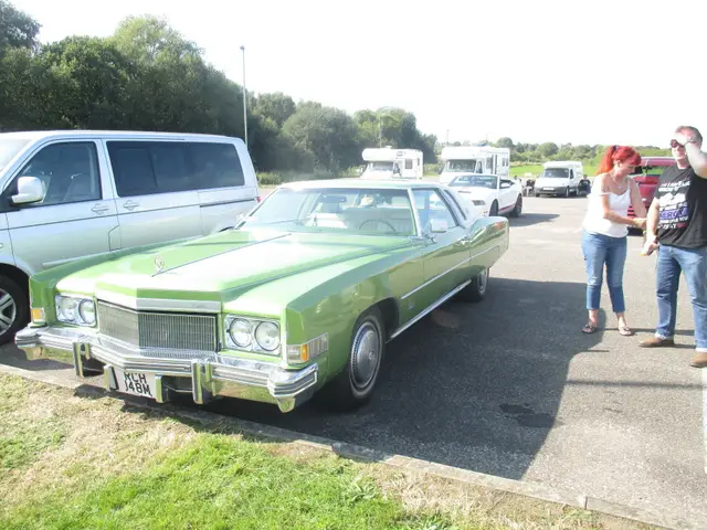 The green Cadillac from the front, with people looking on